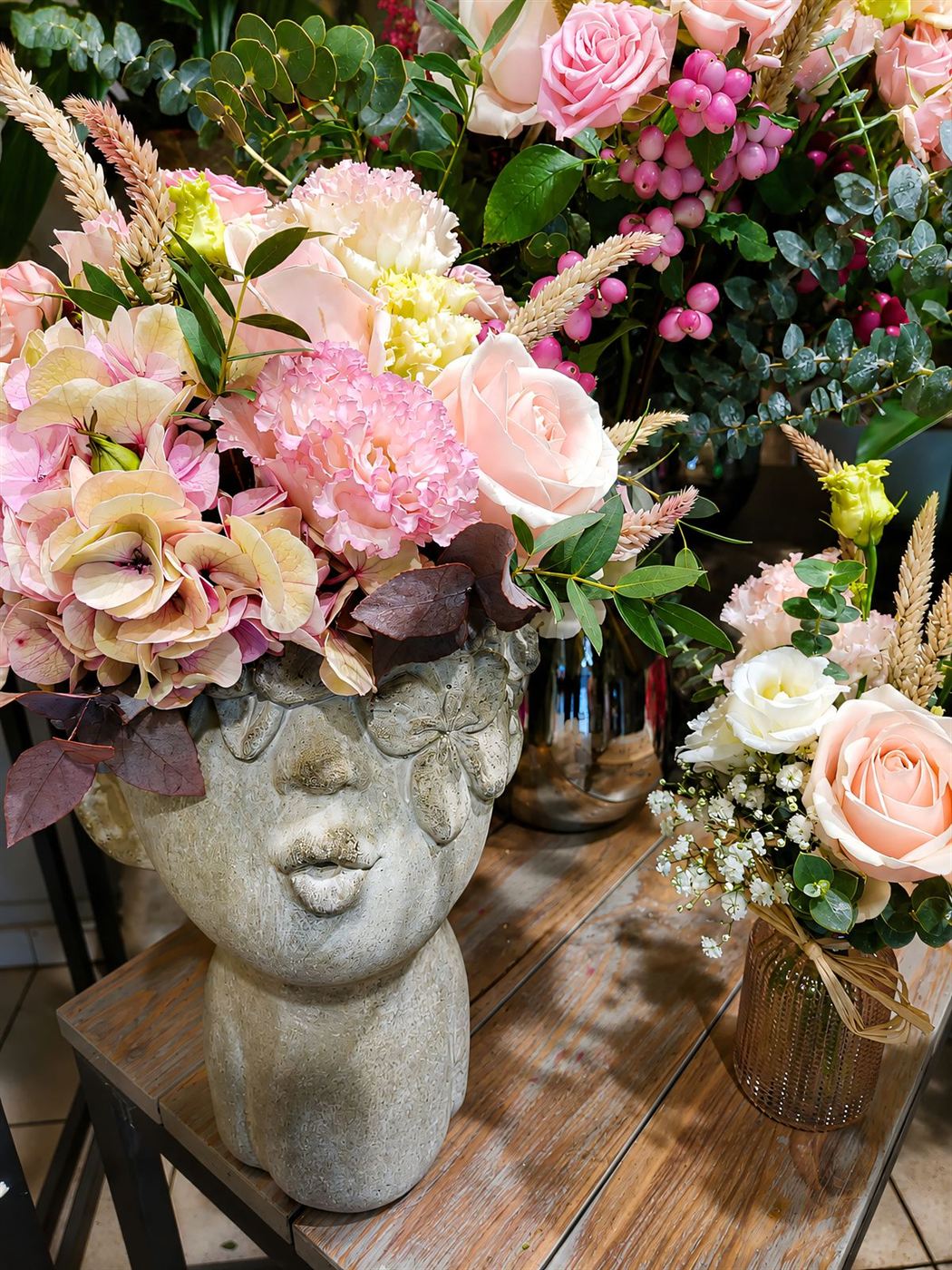 Composition dans vase visage, roses pêche, hortensia rose et gypsophile