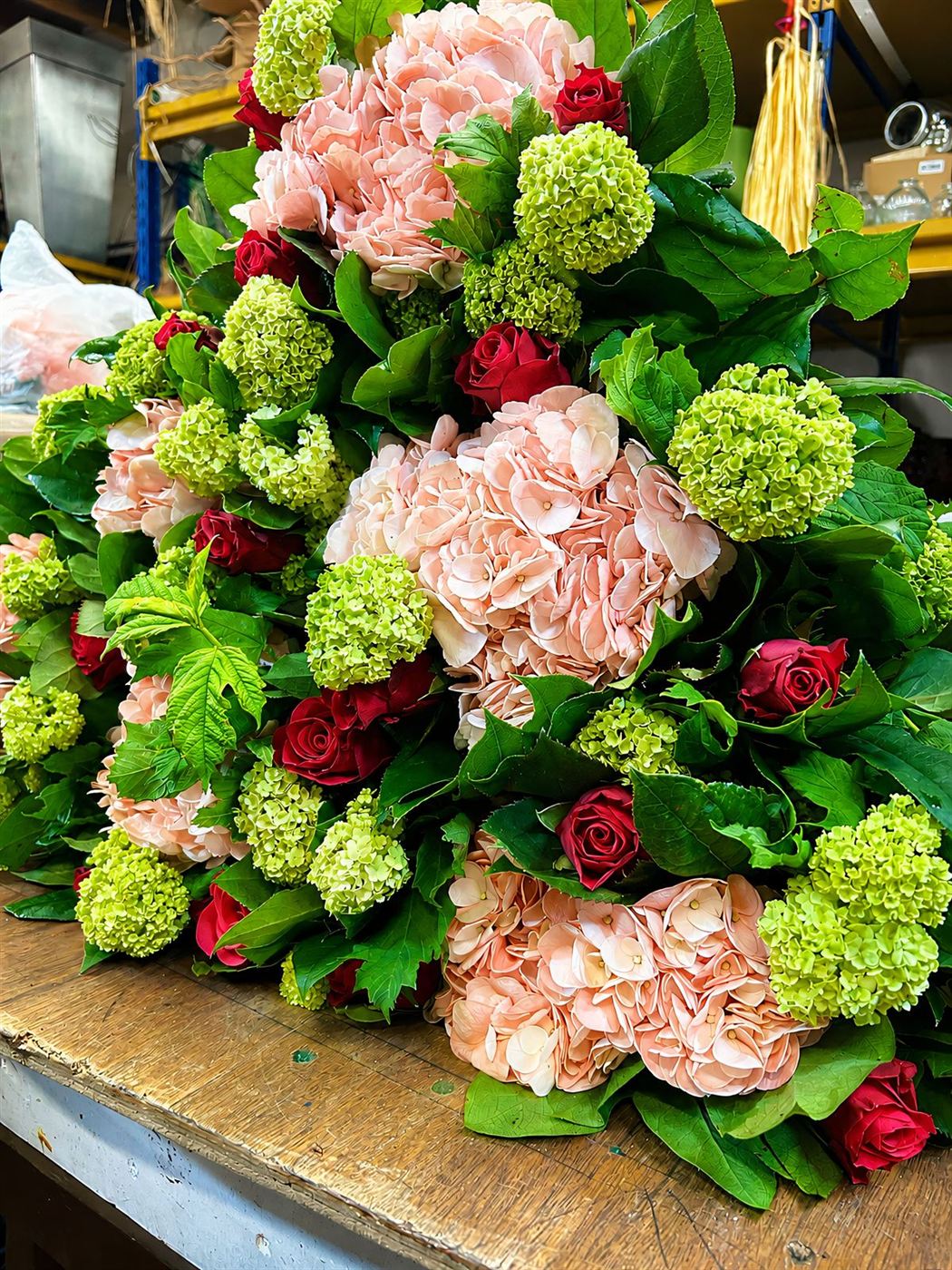 Composition, hortensia pêche, roses rouges et boules de viburnum vertes