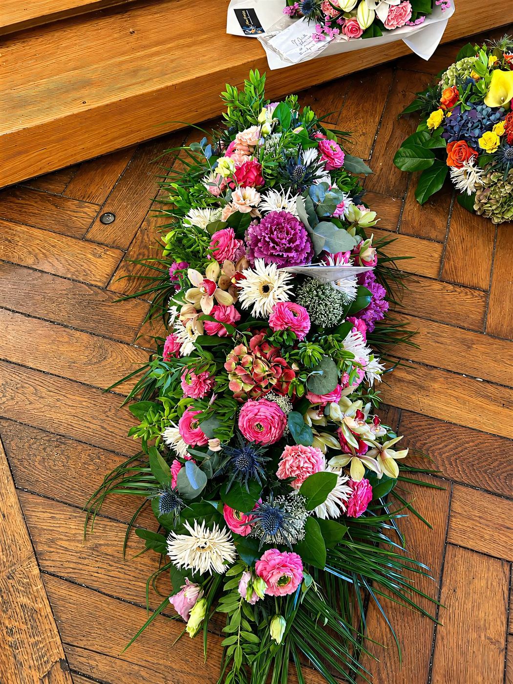 Raquette haute pastel, roses, gerberas et éryngium sur parquet