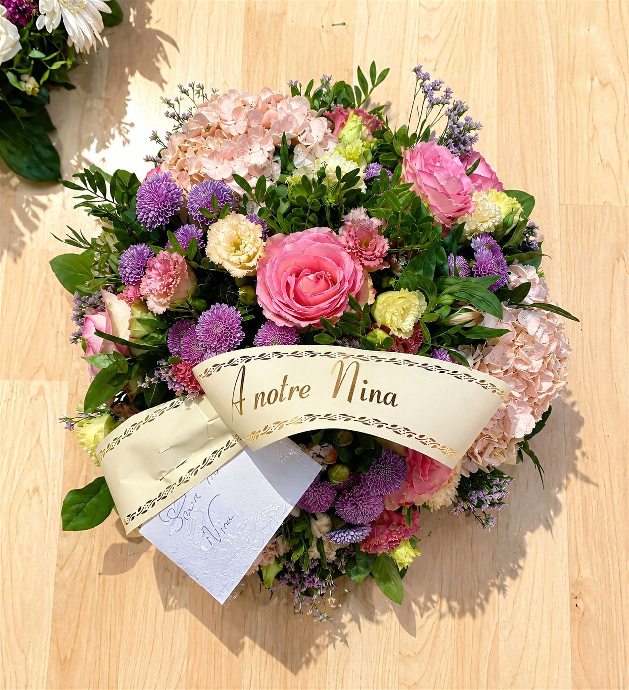 Composition ronde avec ruban personnalisé, roses roses, œillets et allium violet