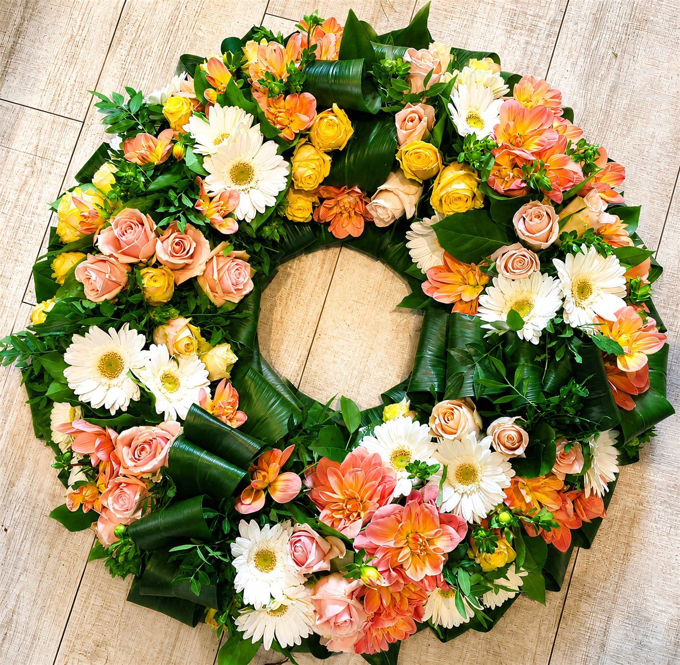 Couronne ronde orange et pêche, gerberas blancs, roses pêche et roses jaunes