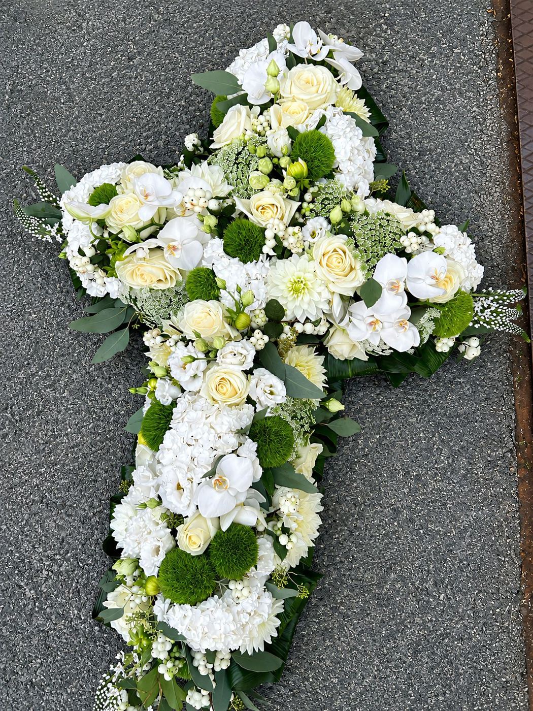 Croix florale blanche, orchidées, roses et chrysanthèmes verts