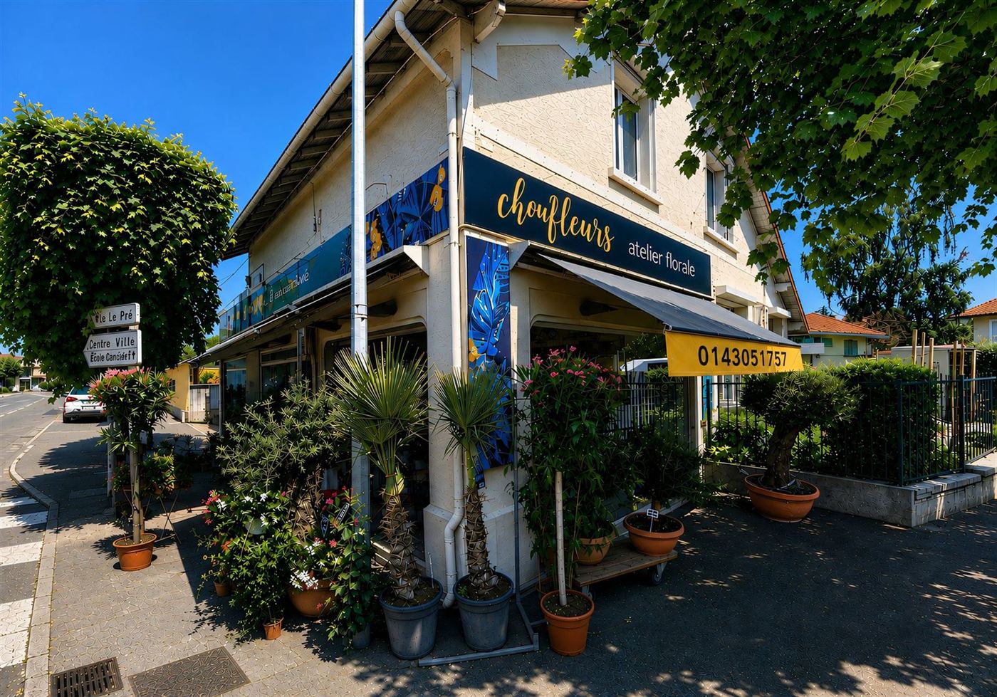 Devanture d'angle atelier floral à Gournay-sur-Marne — palmiers en pot et fleurs au soleil