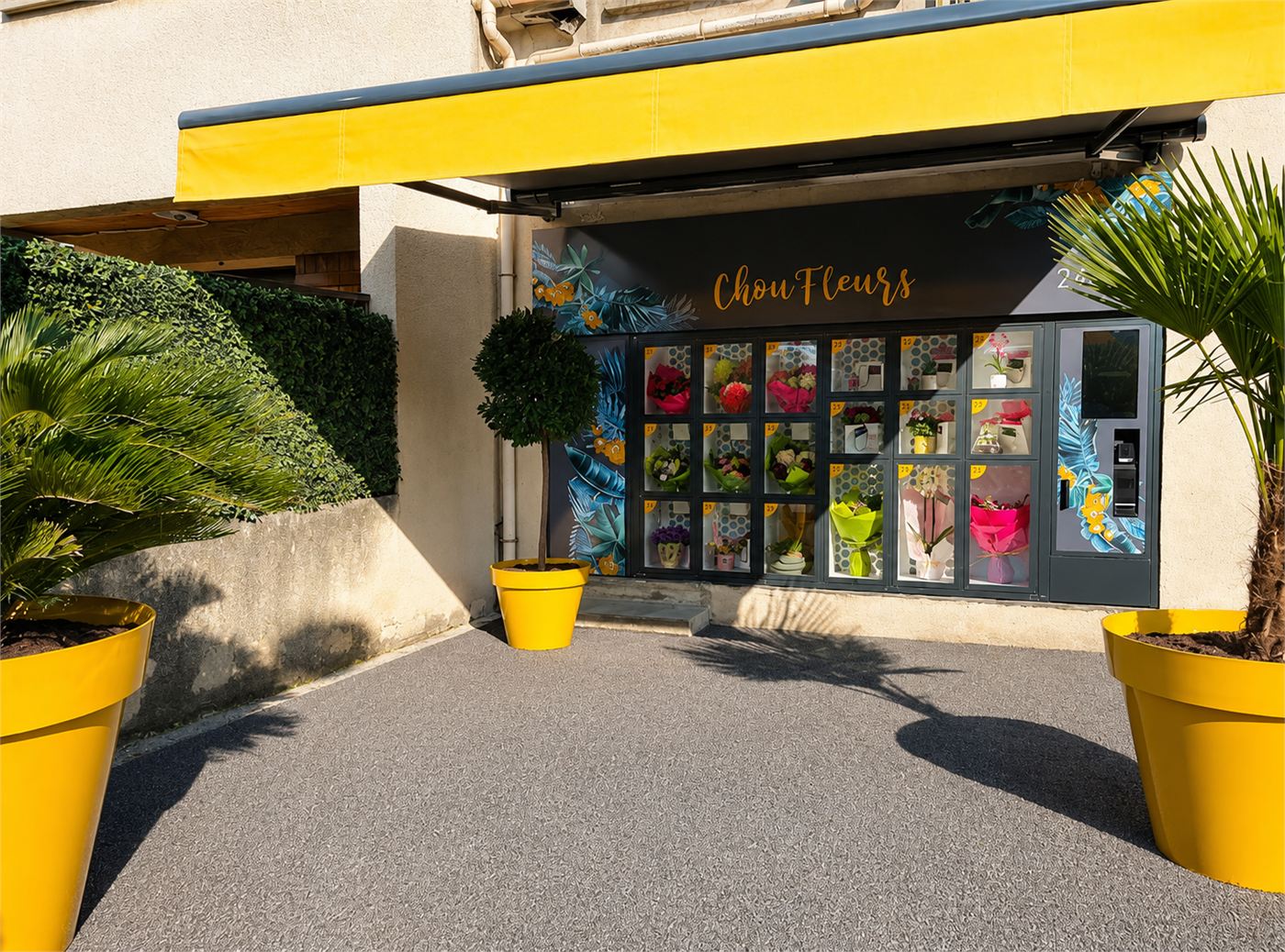 Allée d'accès au Lock'heure, grands pots jaunes et distributeur de bouquets vitré