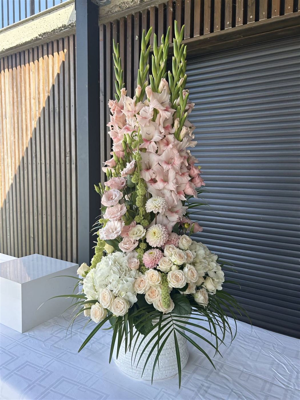 Composition florale sur pied, glaïeuls roses pâles, hortensias et œillets crème