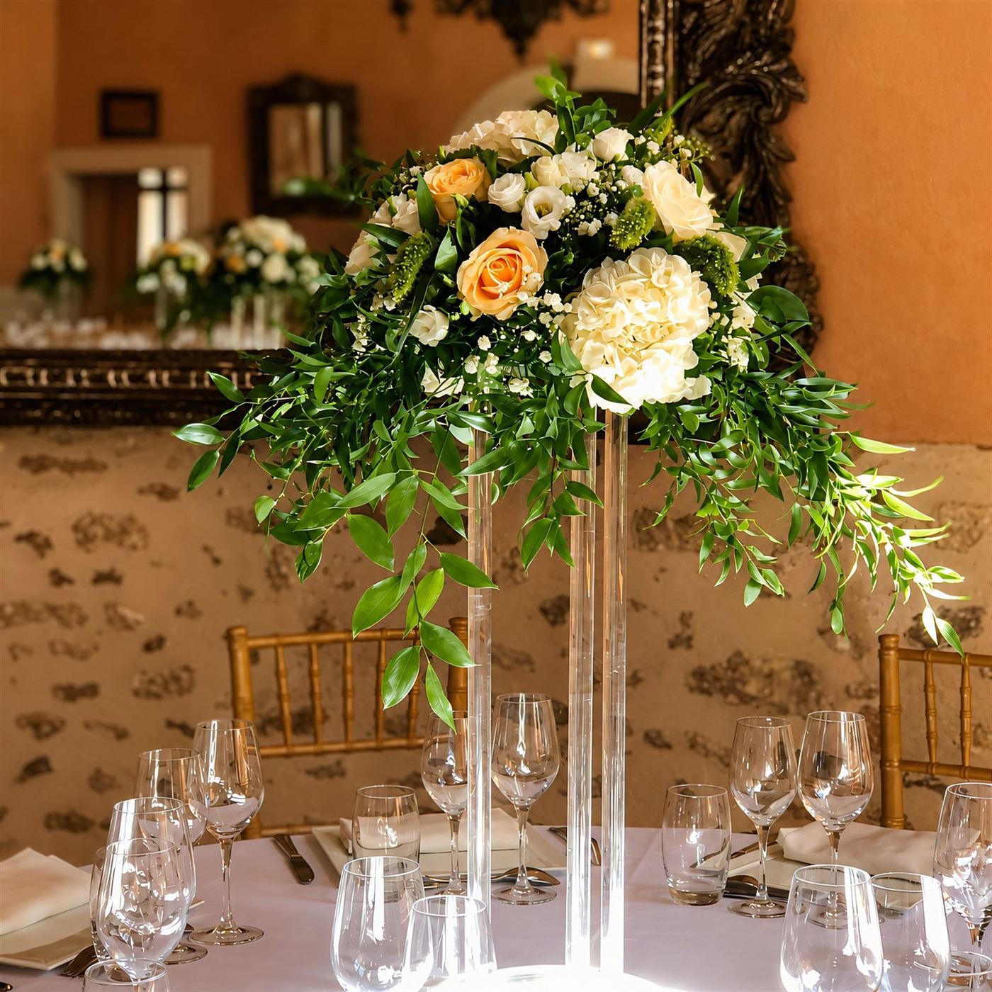 Centre de table haut sur pied transparent, roses pêche, gypsophile et verdure