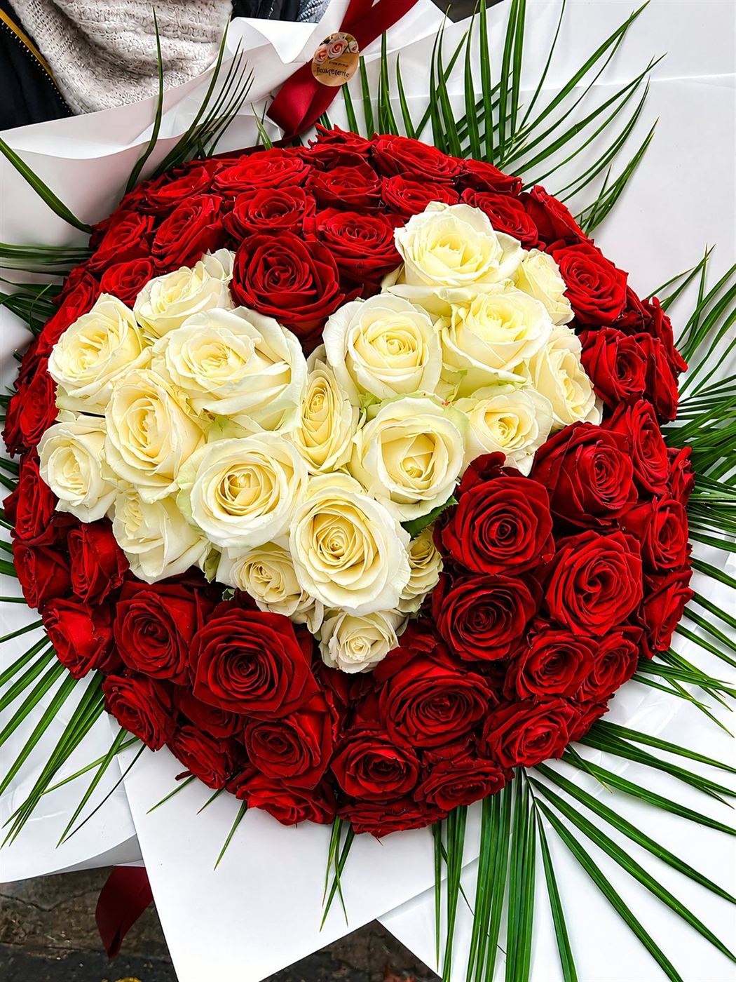 Grand bouquet de 100 roses rouges avec cœur de roses blanches